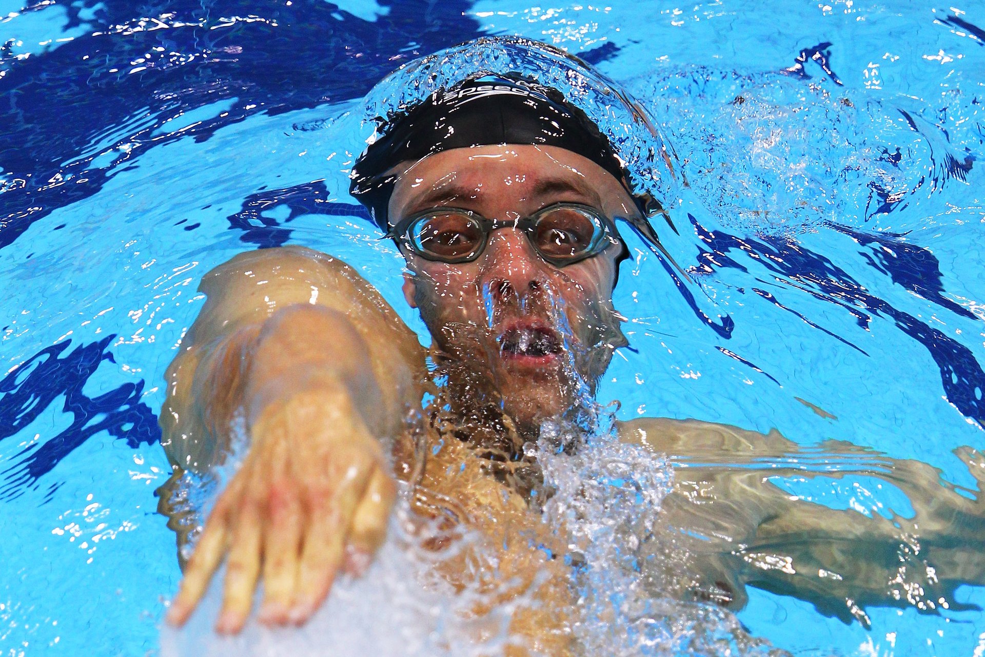Swim coach Marco Loughran standing poolside at an indoor 50m competition pool in Copenhagen